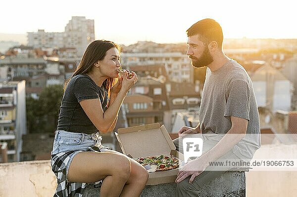 Seitenansicht Paar ißt Pizza im Freien