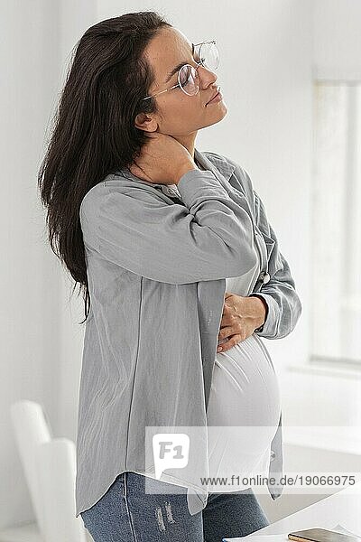 Seitenansicht schwangere Frau hält ihren Hals