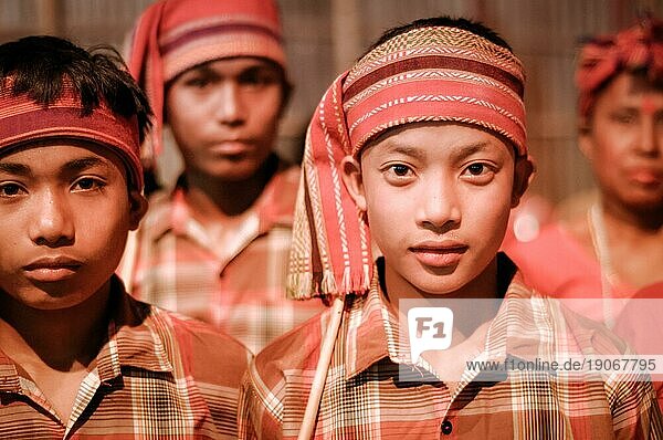 Guwahati  Assam  ca. April 2012: Junge einheimische Jungen in orangefarbenen Kostümen und mit Stirnbändern schauen beim Bihu Fest in Guwahati  in die Kamera. Dokumentarischer Leitartikel