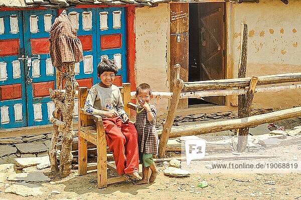 Dolpo  Nepal  etwa im Mai 2012: Junge einheimische Kinder spielen draußen und schauen neugierig in die Fotokamera in Dolpo  Nepal. Ein älteres sitzt auf einem Holzstuhl. Dokumentarischer Leitartikel  Asien