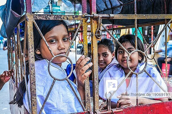 Khulna  Bangladesch  etwa im Juli 2012: Junge Mädchen in weißen Hemden sitzen in einer Rikscha und blicken in Khula  in die Fotokamera. Dokumentarischer Leitartikel  Asien