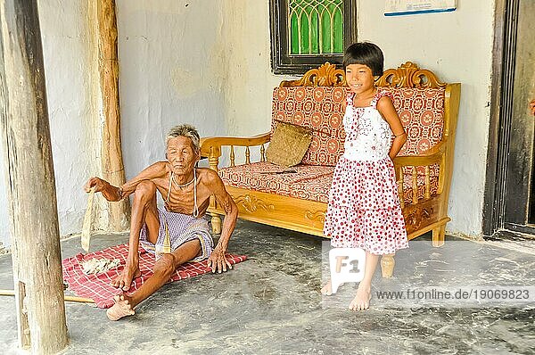 Srimongal  Bangladesch  etwa im Juli 2012: Ein alter  dünner Mann sitzt auf dem Boden und seine Enkelin in einem rotweißen Kleid steht neben ihm in Srimongal  Bangladesch. Dokumentarischer Leitartikel  Asien