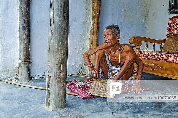 Srimongal  Bangladesch  etwa im Juli 2012: Alter dünner Mann sitzt auf einer karierten Decke auf dem Boden und schaut nach links in Srimongal  Bangladesch. Dokumentarischer Leitartikel  Asien