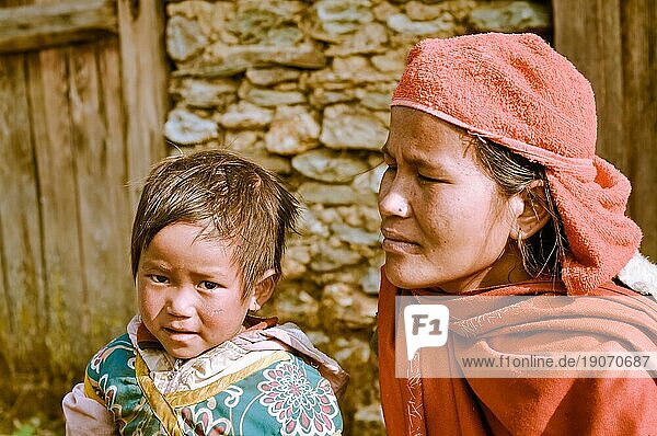 Beni  Nepal  ca. Mai 2012: Foto einer Mutter mit rotem Schal und Kopftuch  die neben ihrer kleinen Tochter mit braunem Haar und braunen Augen in Beni  kniet. Dokumentarischer Leitartikel  Asien