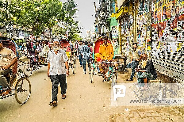 Dhaka  Bangladesch  etwa im Juli 2012: Fußgänger und Menschen auf Rikschas eilen durch eine belebte Straße und schauen in die Kamera in Dhaka  Bangladesch. Dokumentarischer Leitartikel  Asien