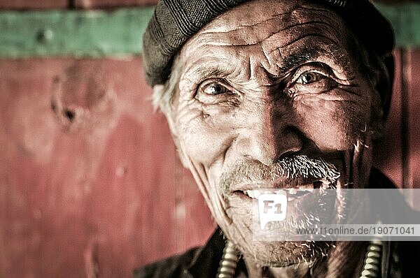 Dolpo  Nepal  etwa im Mai 2012: Alter Mann mit faltigem Gesicht hat braune Mütze auf dem Kopf mit großen braunen Augen in Dolpo  Nepal. Dokumentarischer Leitartikel  Asien