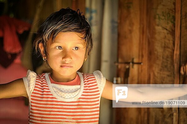 Beni  Nepal  ca. Mai 2012: Ein kleines Mädchen mit Ohrringen und braunen Augen trägt ein rotweißes Kleid und posiert in ihrem Haus in Beni  Nepal. Dokumentarischer Leitartikel  Asien