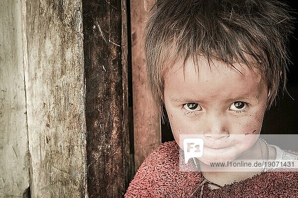 Dolpo  Nepal  ca. Mai 2012: Kleines Mädchen mit braunen  glitzernden Augen  bekleidet mit einem roten Pullover  schaut neugierig in die Kamera in Dolpo  Nepal. Dokumentarischer Leitartikel  Asien