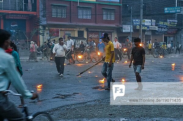 Nepal  ca. Mai 2012: Foto von Menschen  die mit brennenden Fackeln in den Händen an einem regnerischen Tag während des Generalstreiks in Nepal auf der Straße gehen oder Fahrrad fahren. Dokumentarischer Leitartikel  Asien
