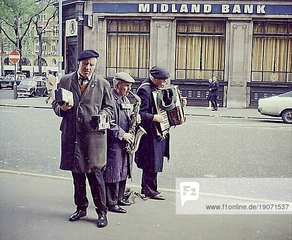 Drei blinde Männer  davon zwei Strassenmusiker mit Saxophon und Akkordeon und einer mit Sammelbüchse mit Aufschrift HELP THE BLIND vor einer Filiale der Midland Bank  London  Großbritannien  Großbritannien  Europa