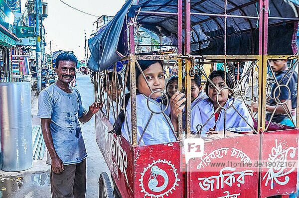 Khulna  Bangladesch  etwa im Juli 2012: Lächelnde Kinder in einer Rikscha lächeln in die Kamera und ein Mann mit Schnauzbart steht neben ihnen und lächelt in Khula  Bangladesch. Dokumentarischer Leitartikel  Asien