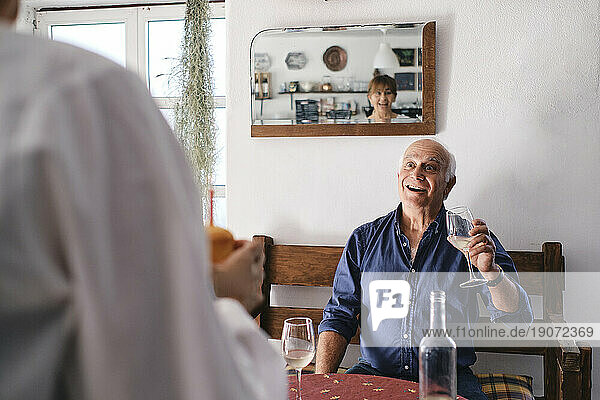 Surprised senior man holding wine glass and looking at woman with cupcake