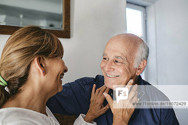 Happy senior woman embracing and having fun with man in cafe
