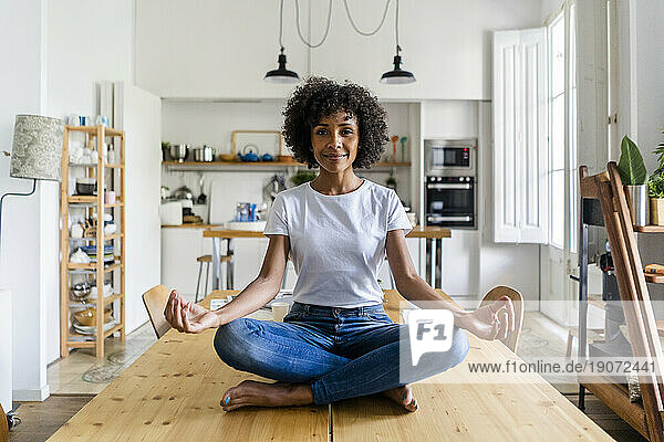 Portrait of smiling woman in yoga pose on table at home
