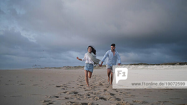 Happy young couple running together at beach