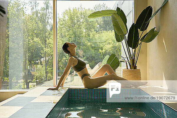 Beautiful woman reclining by hot tub at spa