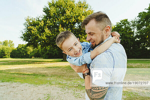 Playful father holding son on field