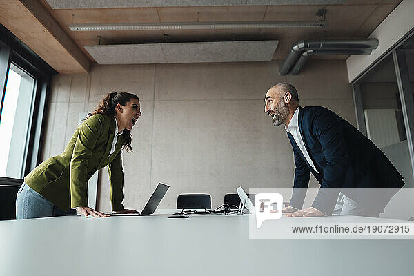 Businesswoman arguing with businessman at desk in office