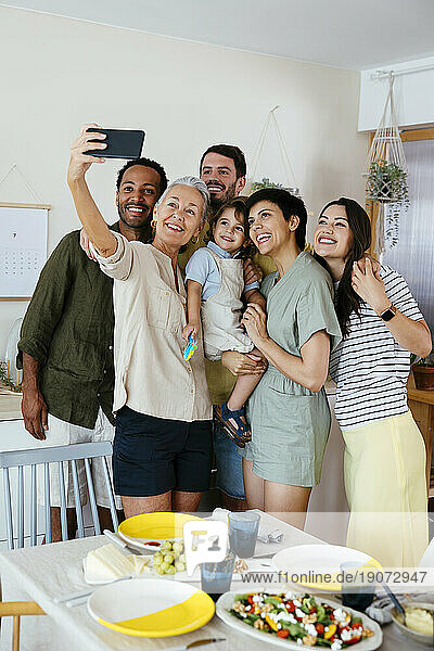 Happy family taking selfie with smart phone in kitchen