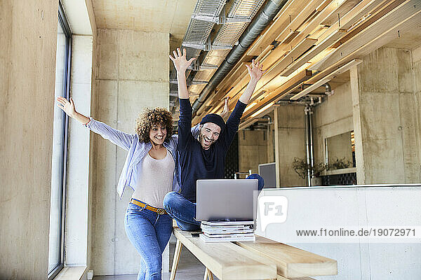 Excited man and woman with laptop in modern office