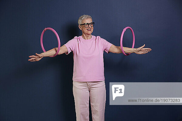 Senior woman practicing with hoops against blue background