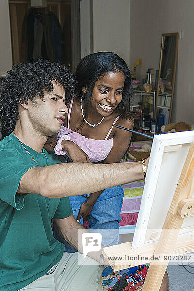 Smiling couple painting on canvas at home