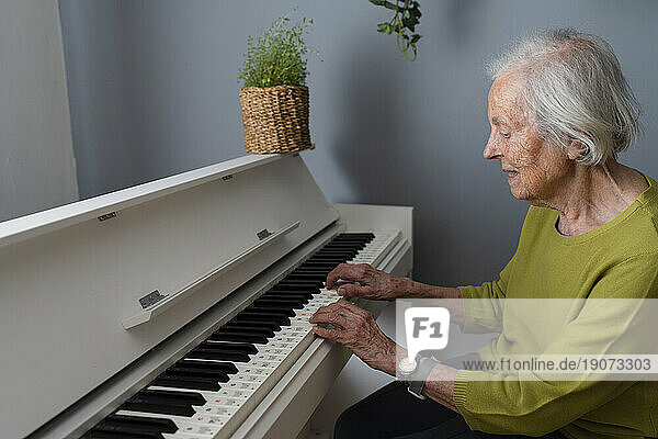 Senior woman playing piano at home