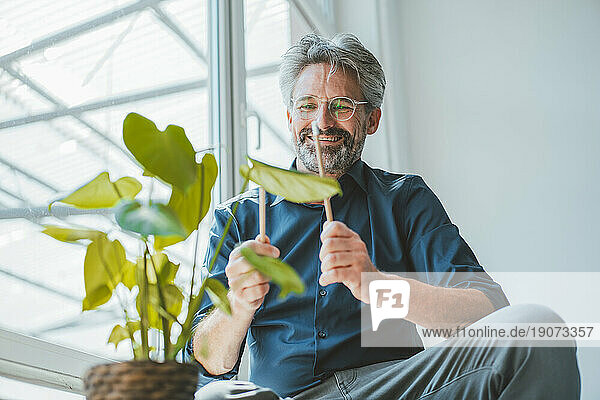 Smiling businessman playing with sticks at office