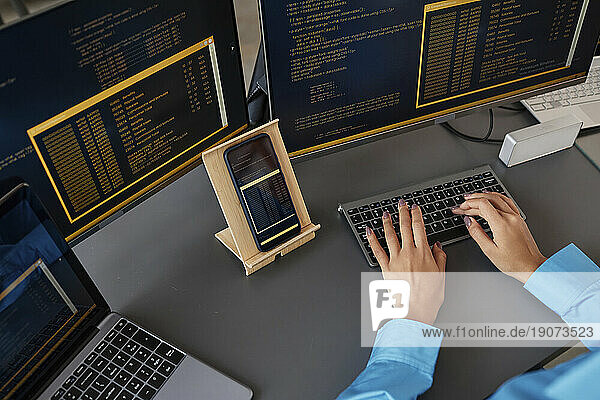 Hands of computer programmer typing on keyboard at desk