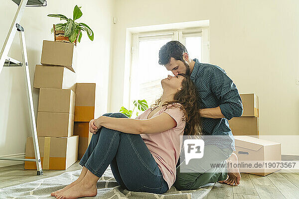 Romantic man kneeling and kissing girlfriend at new home
