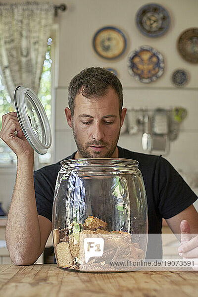 Man sitting in kitchen  looking in cookie jar