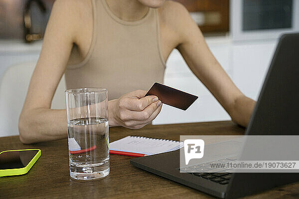 Freelancer using credit card for online payment on laptop at home
