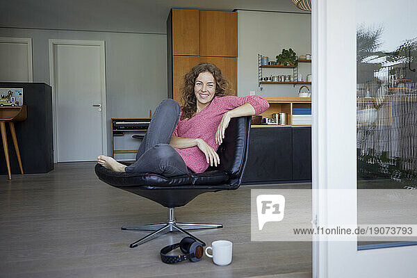 Smiling woman sitting on chair at home