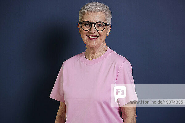 Portrait of smiling senior woman against blue background