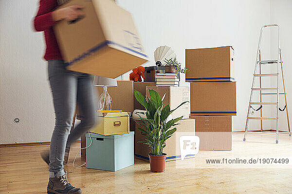 Woman carrying cardboard box in a new home