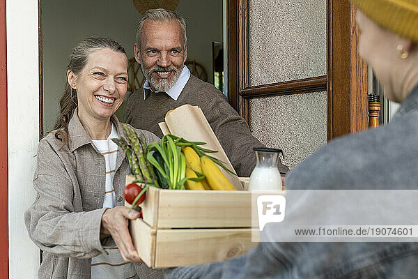 Happy mature couple receiving groceries via home delivery