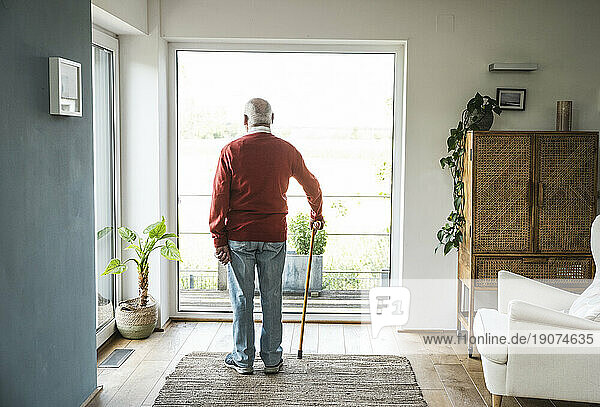 Contemplative senior man standing in front of window