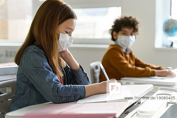 Seitenansicht Kinder mit medizinischen Masken im Klassenzimmer beim Lernen