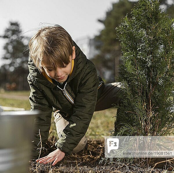 Vorderansicht junger Junge pflanzt Baum im Freien