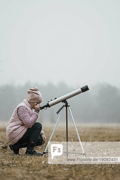 Seitenansicht Kind mit Teleskop im Freien