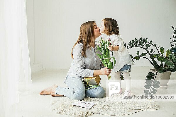 Mutter mit Blumen Tochter küssend
