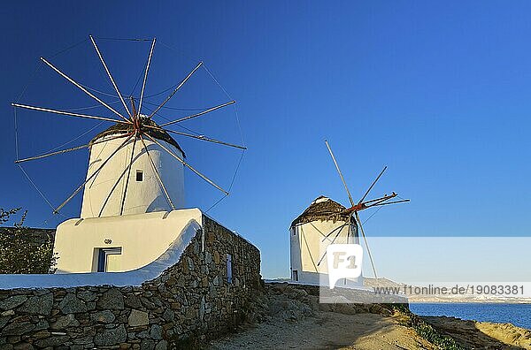 Berühmte Touristenattraktion von Mykonos  Kykladen  Griechenland. Zwei traditionelle weiß getünchte Windmühlen am Wasser und die Stadt Chora. Sommer  Morgen  klarer blauer Himmel  Reiseziel  ikonische Ansicht. Frontalaufnahme