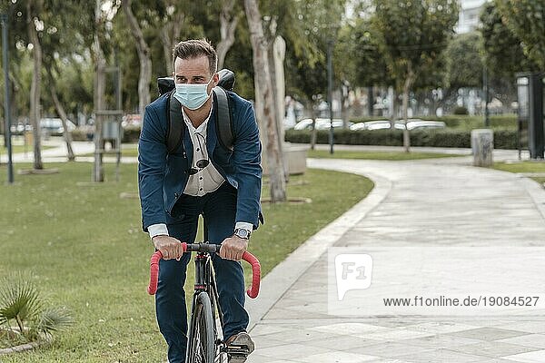 Mann fährt Fahrrad und trägt eine medizinische Maske