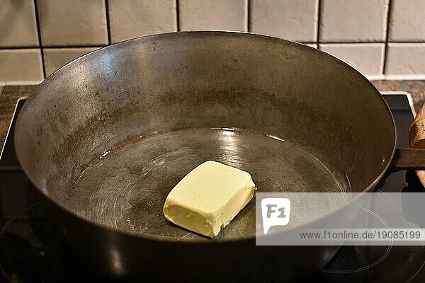 Zubereitung von Dampfnudeln  Butter in rustikaler alter Dampfnudelpfanne  typisch traditionell bayerische Küche  Deutschland  Europa