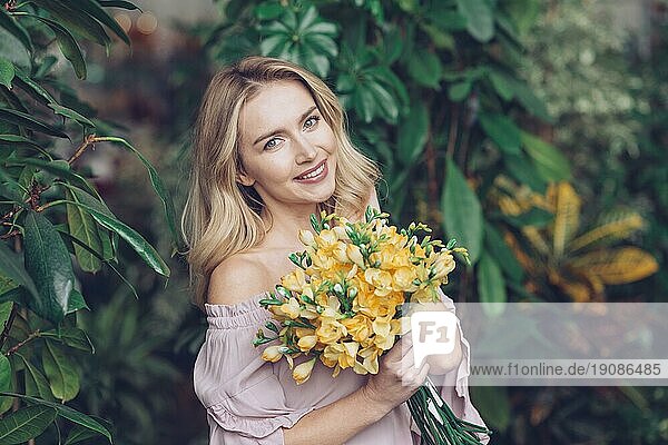 Porträt blonde junge Frau mit gelbem Blumenstrauß