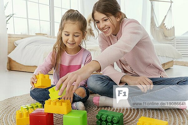 Vorderansicht zwei lächelnde Schwestern spielen mit Spielzeug nach Hause