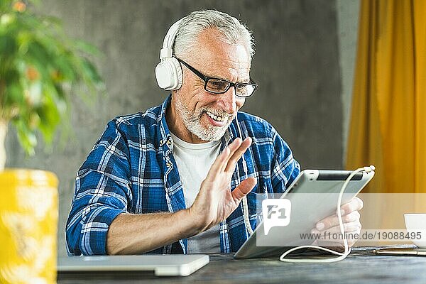 Lächelnder älterer Mann sagt hallo digitales Tablet