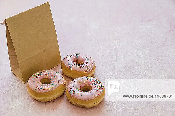 Drei leckere Donuts mit paketrosa Hintergrund