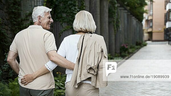 Rückenansicht umarmte älteres Paar beim Spaziergang im Freien