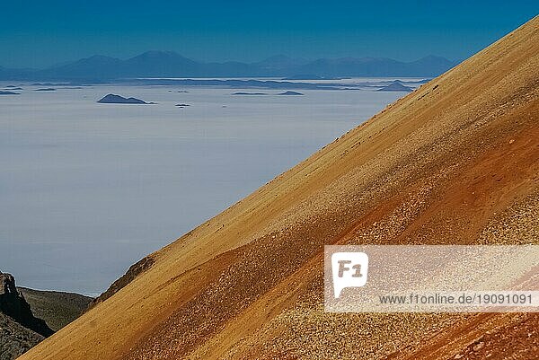 Foto von einem Berg mit orangefarbenem Sand und einem nebelverhangenen Tal in der Ferne in Bolivien